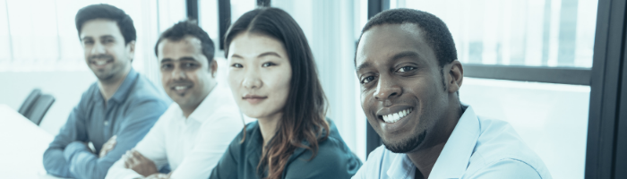 A row of international students sit in a row in a brightly lit white room