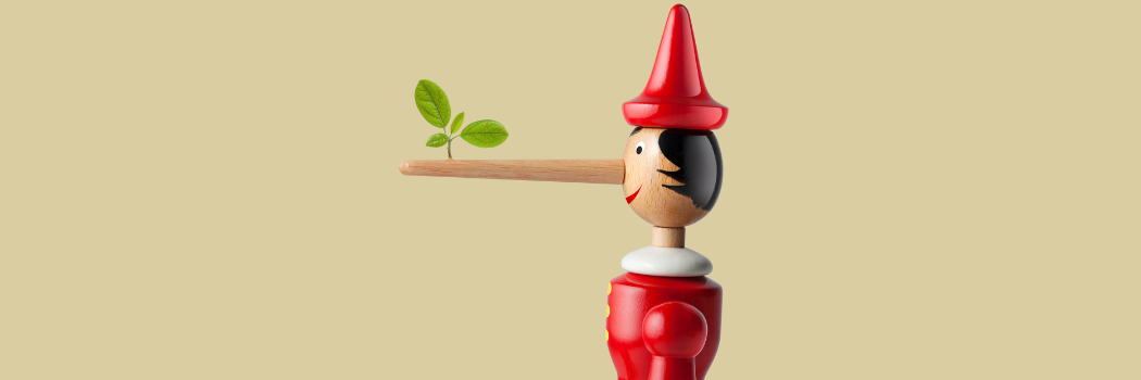Pinocchio puppet in red outfit with long nose and small green plant growing out of it