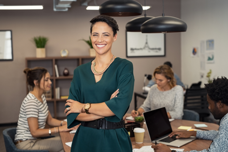 Business People sat around a table with woman stood at the front