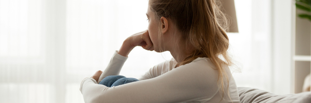 Upset woman sitting on couch alone at home