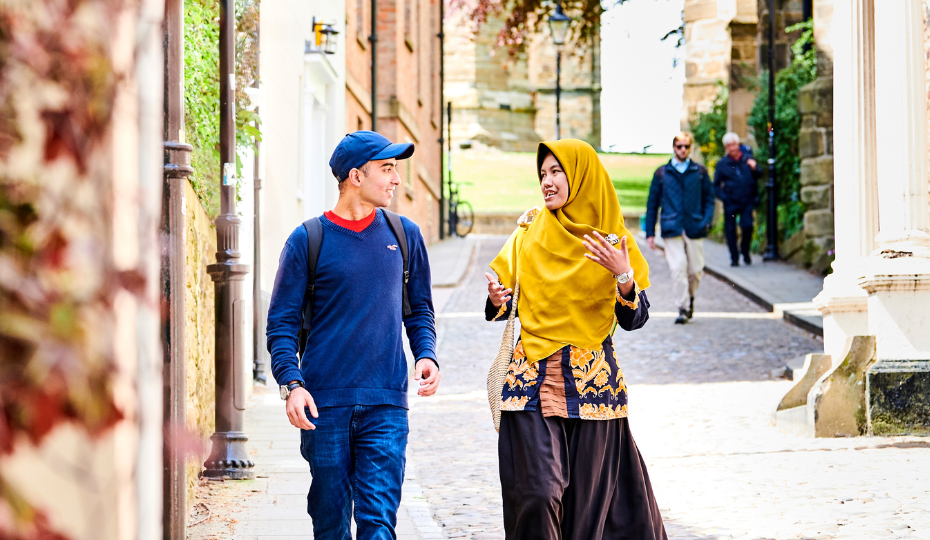 Two students talk as they walk down the cobbled street of Bow Lane, Durham