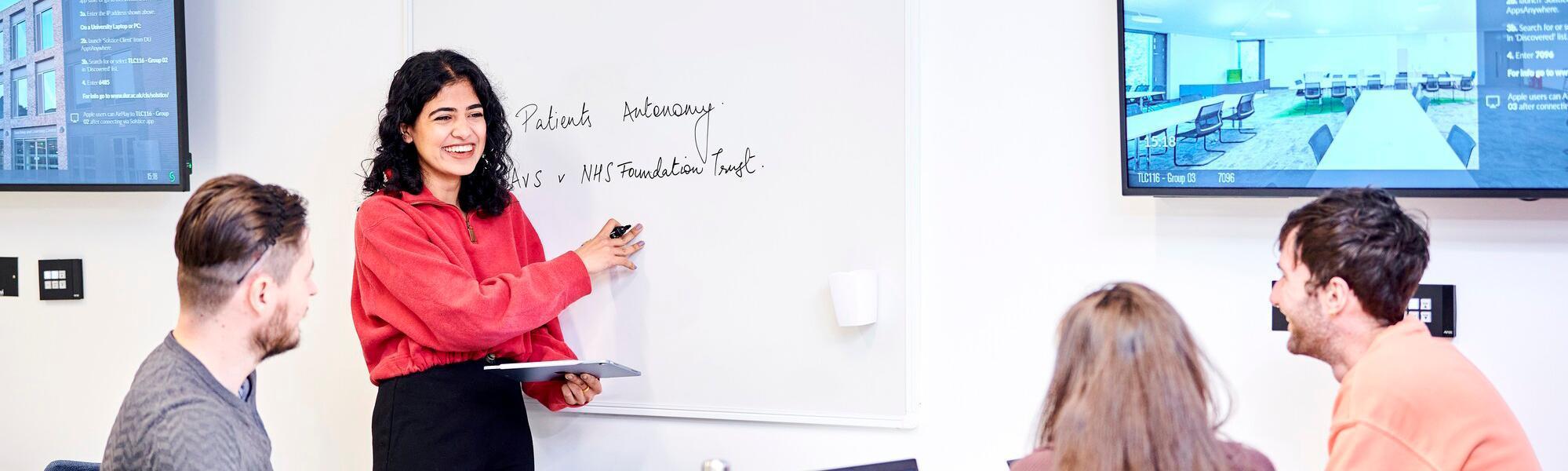 Seminar using a whiteboard and students with laptops