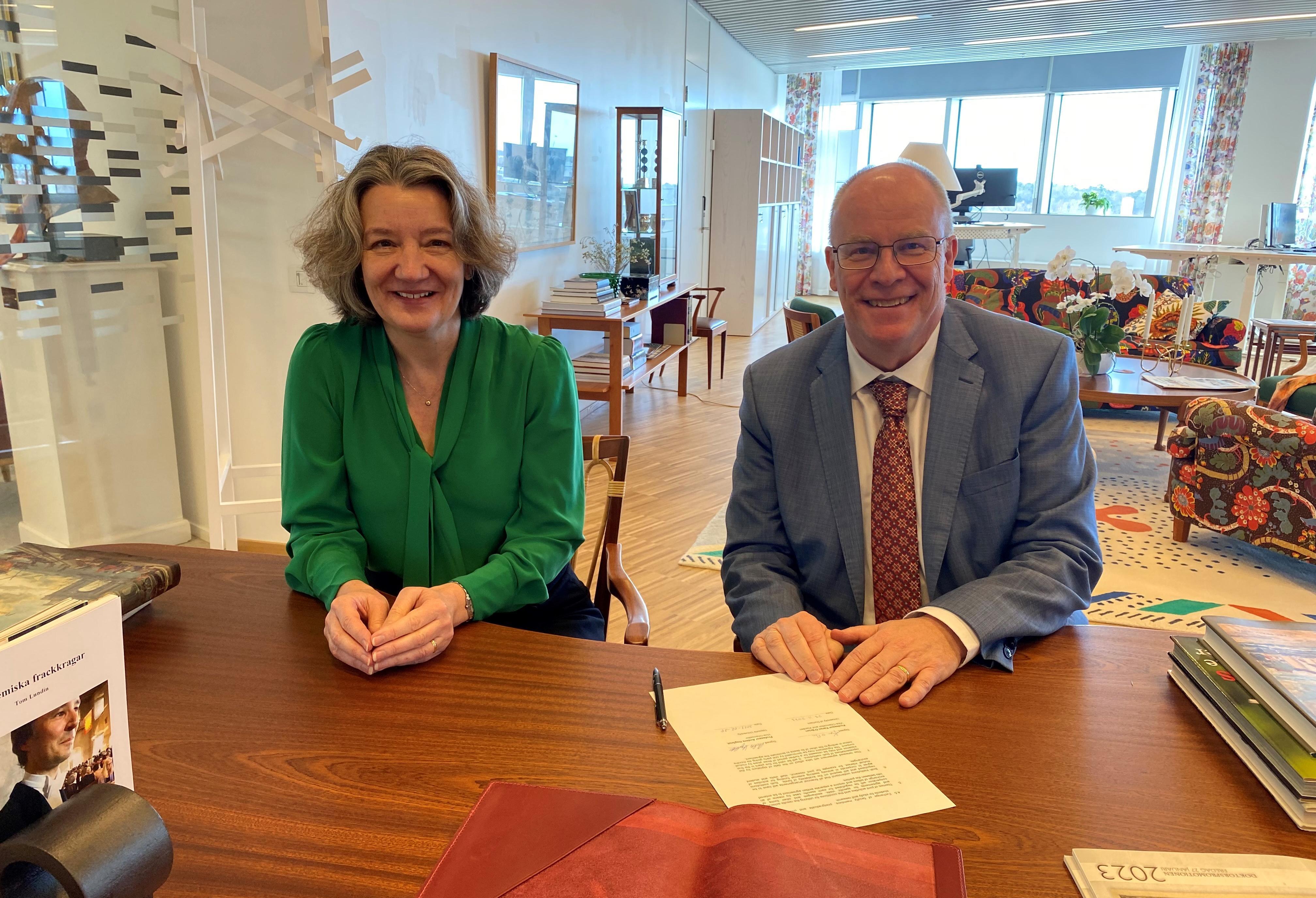 Two people sitting at a desk with a signed document