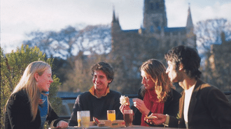 A group of students outside having lunch with cathedral in the background