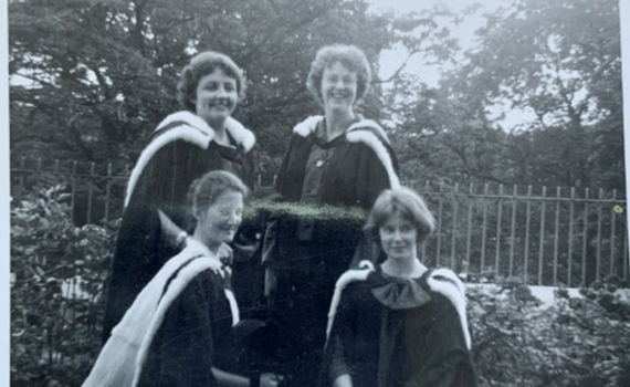 Four female graduates in gowns in black and white from the past