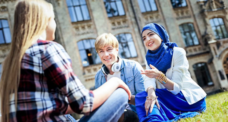 Three students sitting outside on the grass