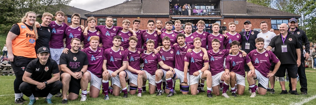 A male rugby team in two lines wearing purple jerseys
