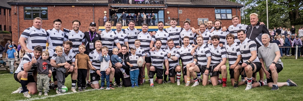 A male rugby team in two lines wearing horizontal black and white striped jerseys