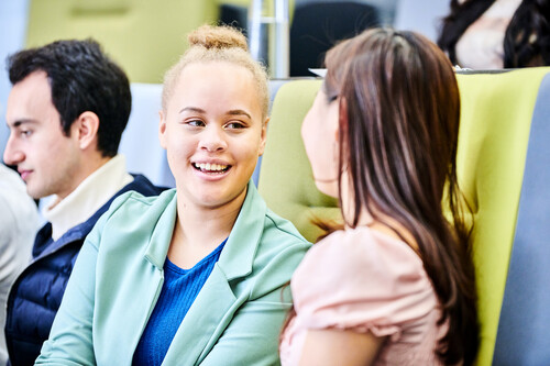 Two students looking at each other and smiling in a lecture theatre