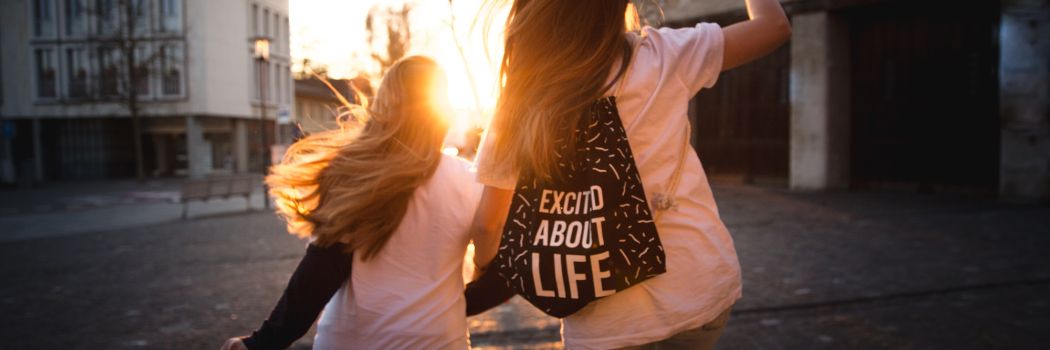 Two girls skipping towards the sunset