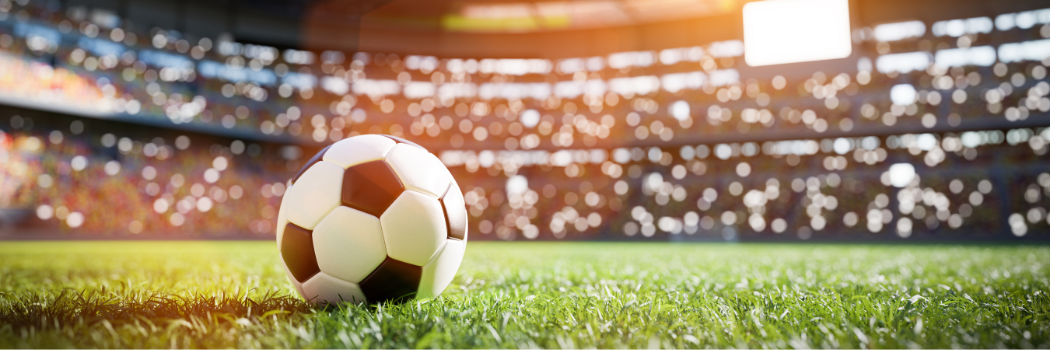 A black and white football on the grass in a stadium.