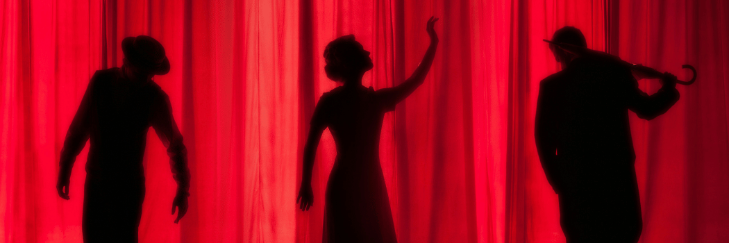 Three silhouettes on stage behind a theatre curtain