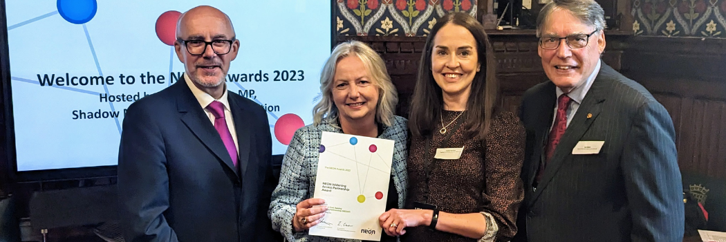 A group of four adults holding an award certificate