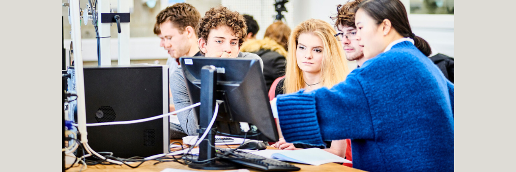 A group of students sitting at a desk looking at a computer screen