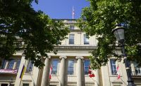 A building with trees in the foreground, Canadian flags