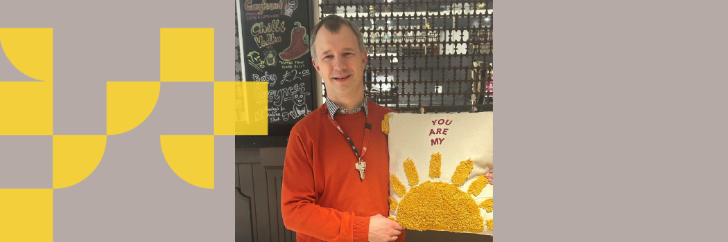 A picture of Peter Swift, former VP of Grey College holding a cushion