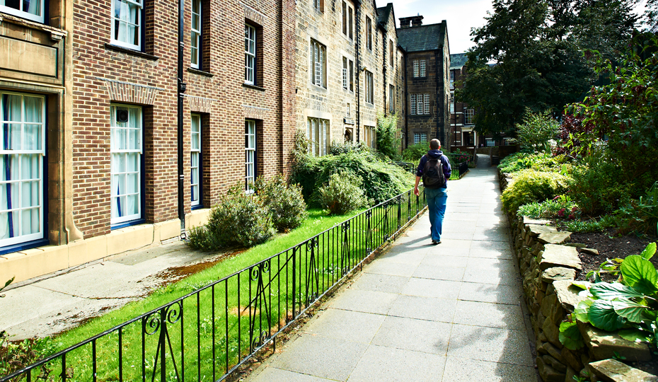A person walking along a college footpath on a summer day