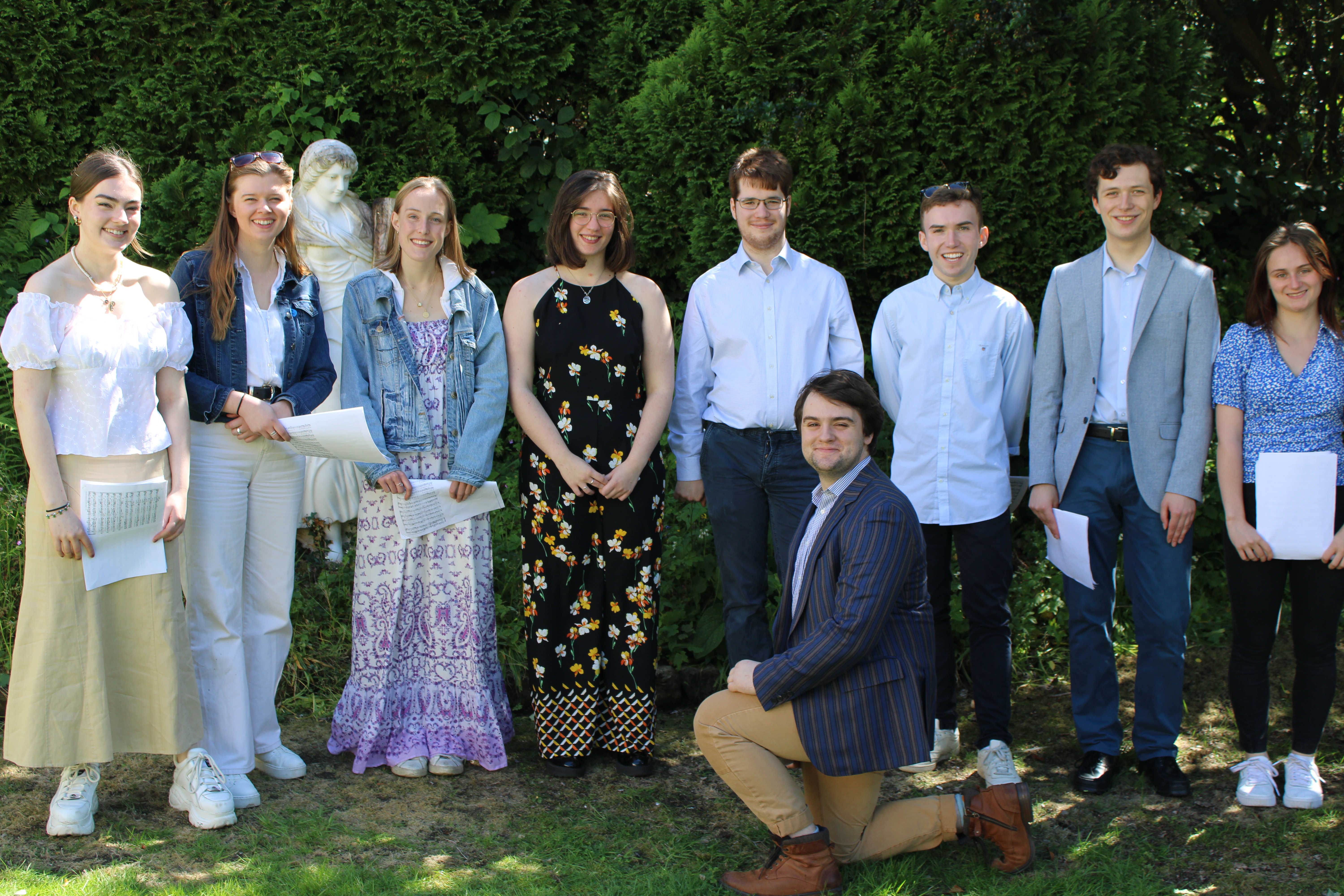 Group of students standing in a semi circle ready to sing in the garden