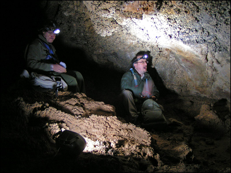 Two archaeologists taking measurements in a cave