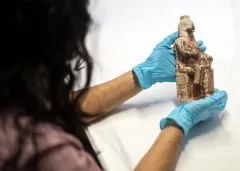 Close-up of a person's hands - they are wearing blue protective gloves and holding an Egyptian artefact