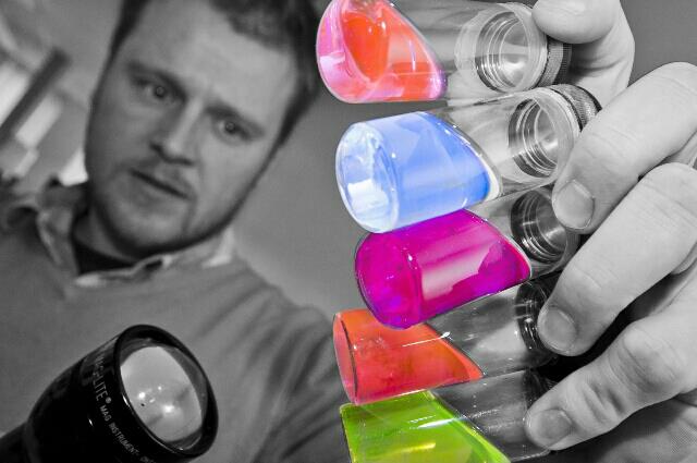 Man shining a torch on coloured test tubes