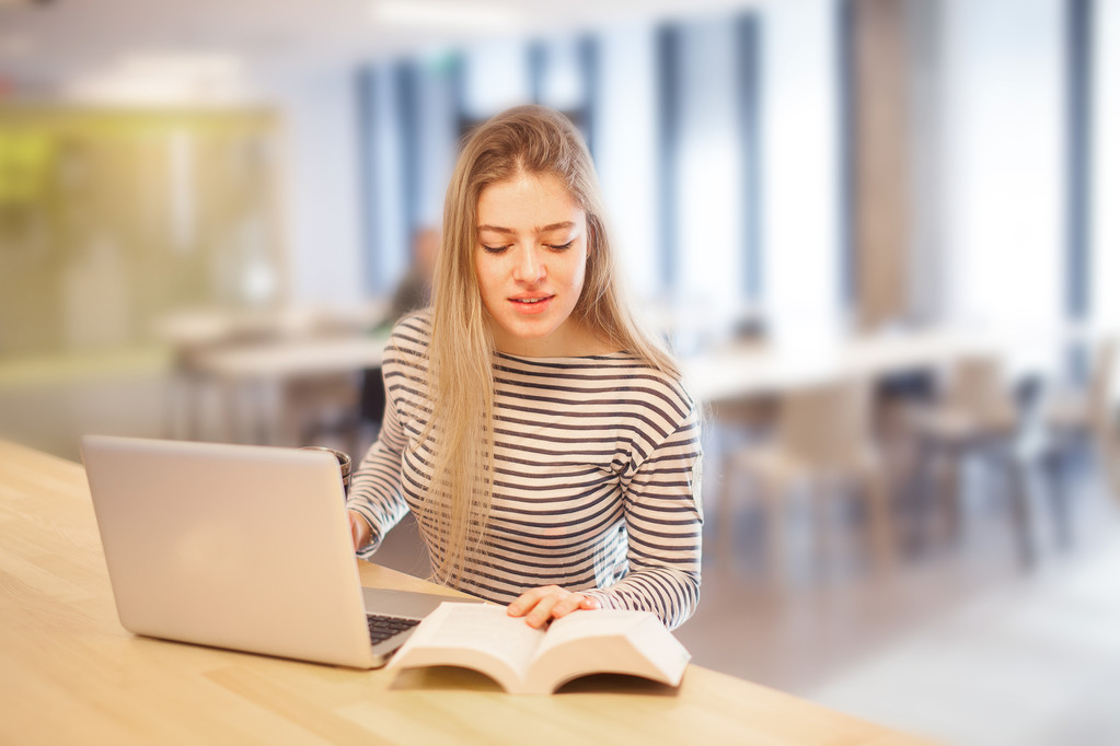 A student with laptop and an open book