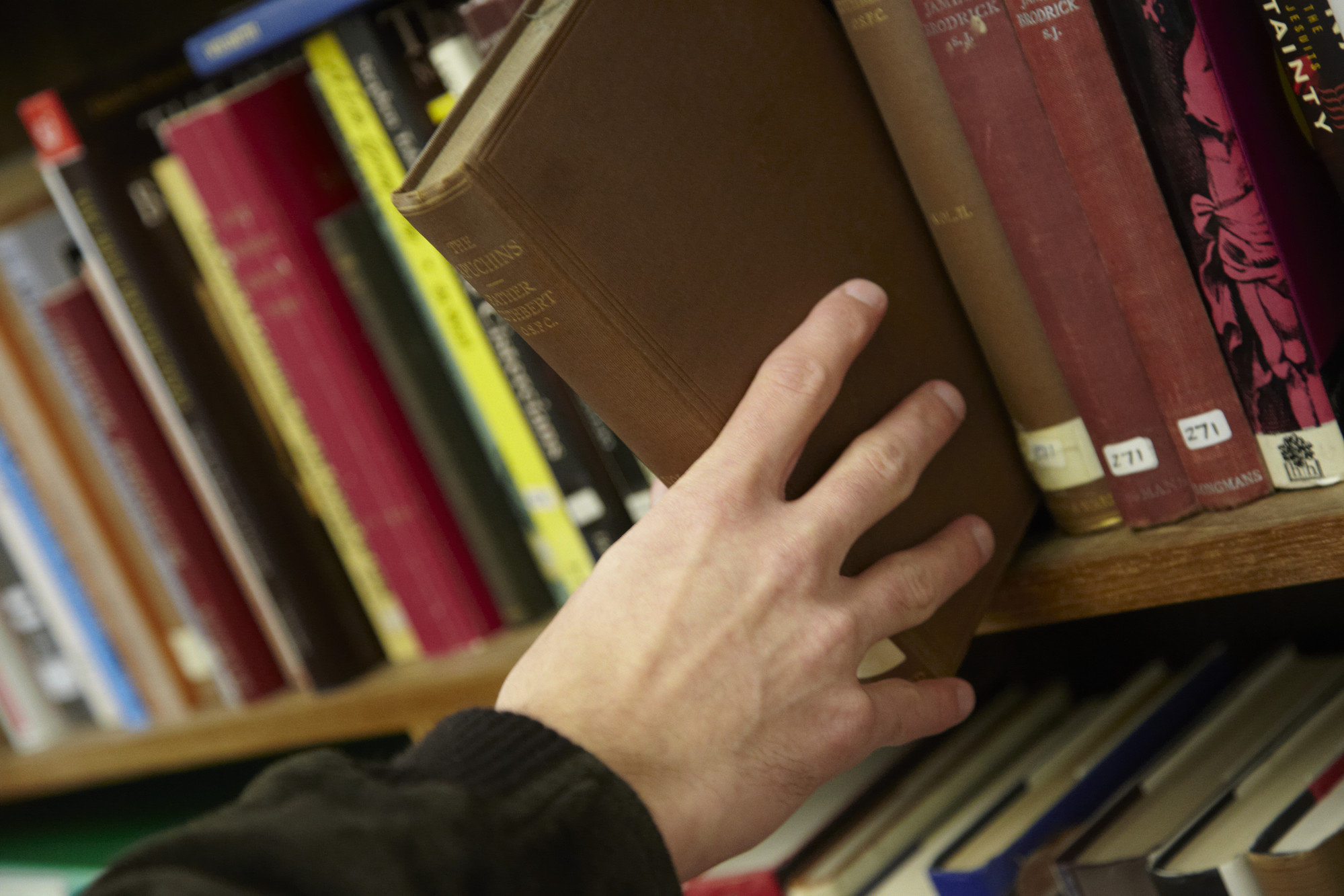 Person taking Theology book off a shelf