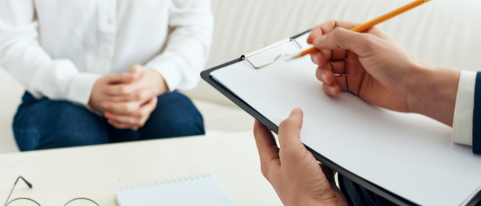 Male hands holding clipboard assessing seated woman