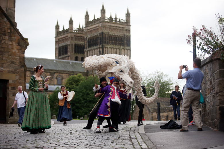 Photograph of a large white dragon puppet dancing in front of a cathedral