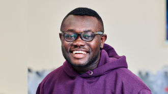 Picture of a male student wearing a purple hoodie and glasses.