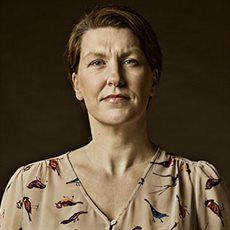 Woman with short hair in a beige blouse. Black background