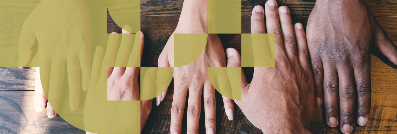 Five hands of different ethnicities next to each other on a table