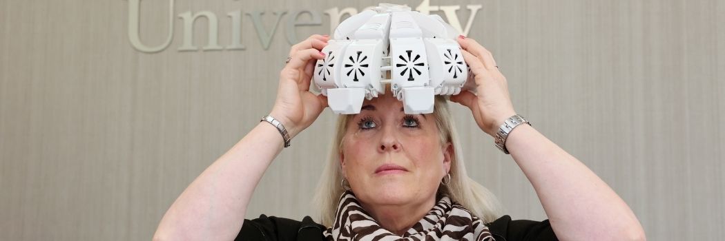 Patient wearing a specially adapted helmet which delivers infrared light deep into the brain