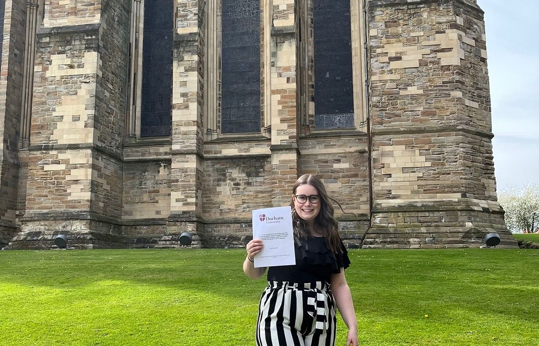A student holding her dissertation outside Durham Cathedral