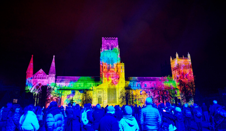 Durham Cathedral illuminated with art with crowds in the foreground