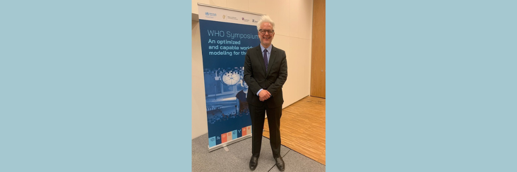 Professor Castellani is pictured at the WHO Symposium standing in front of a banner