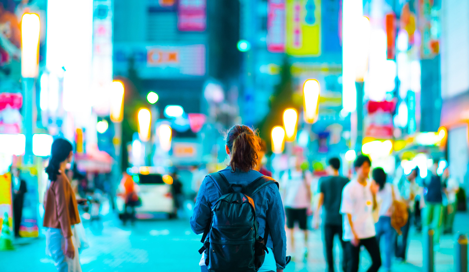 A student walks through a busy neon lit city centre