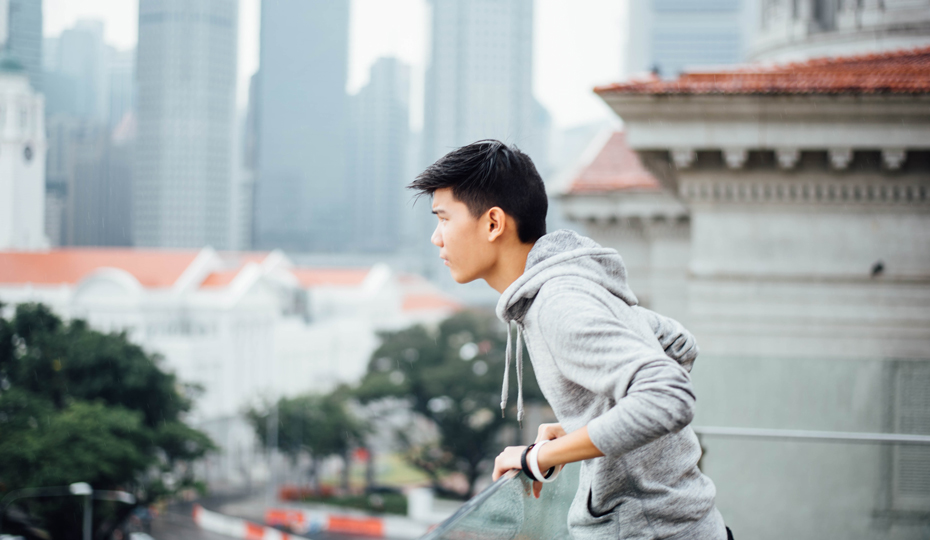 A student on a balcony looks out across a busy city