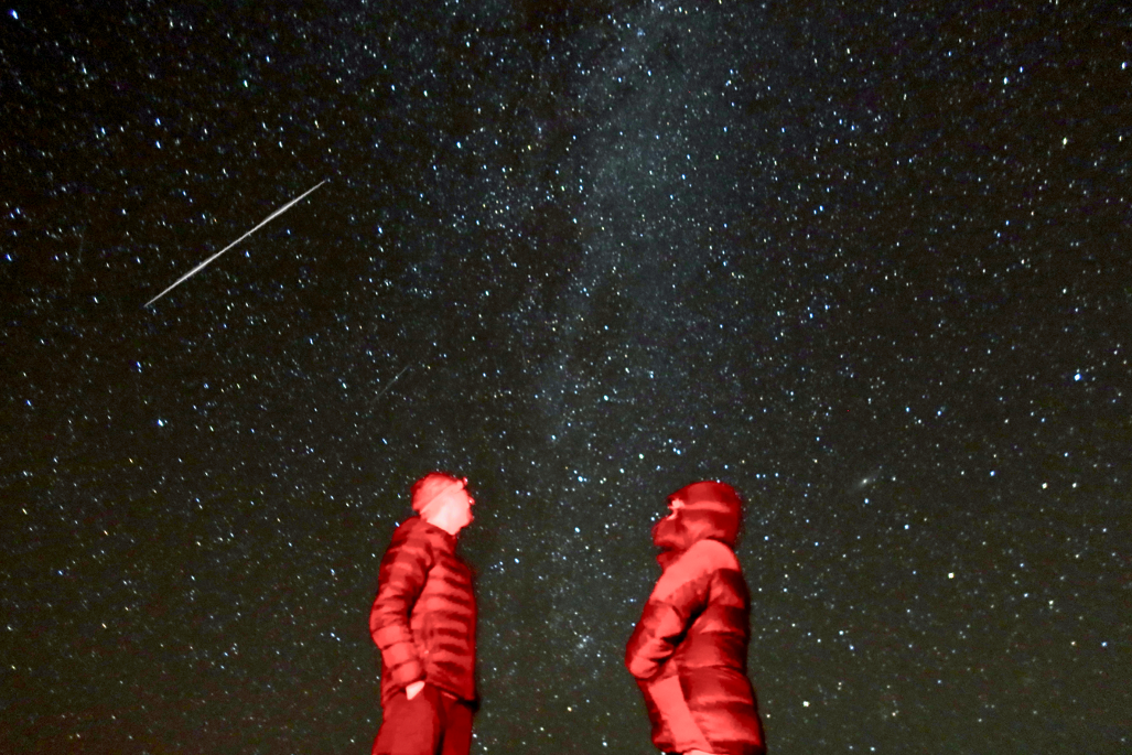 Two people talking at night with satellite flash