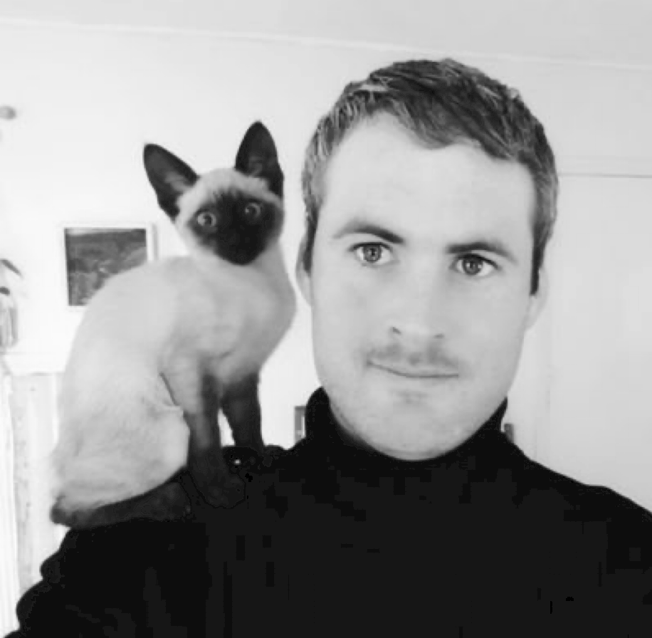A black and white photo of a white man with a cat on his shoulder