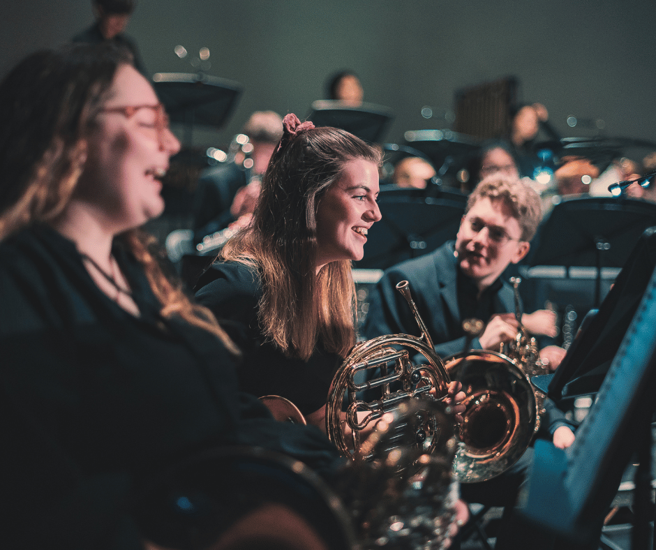 French Horn players smiling at a performance of