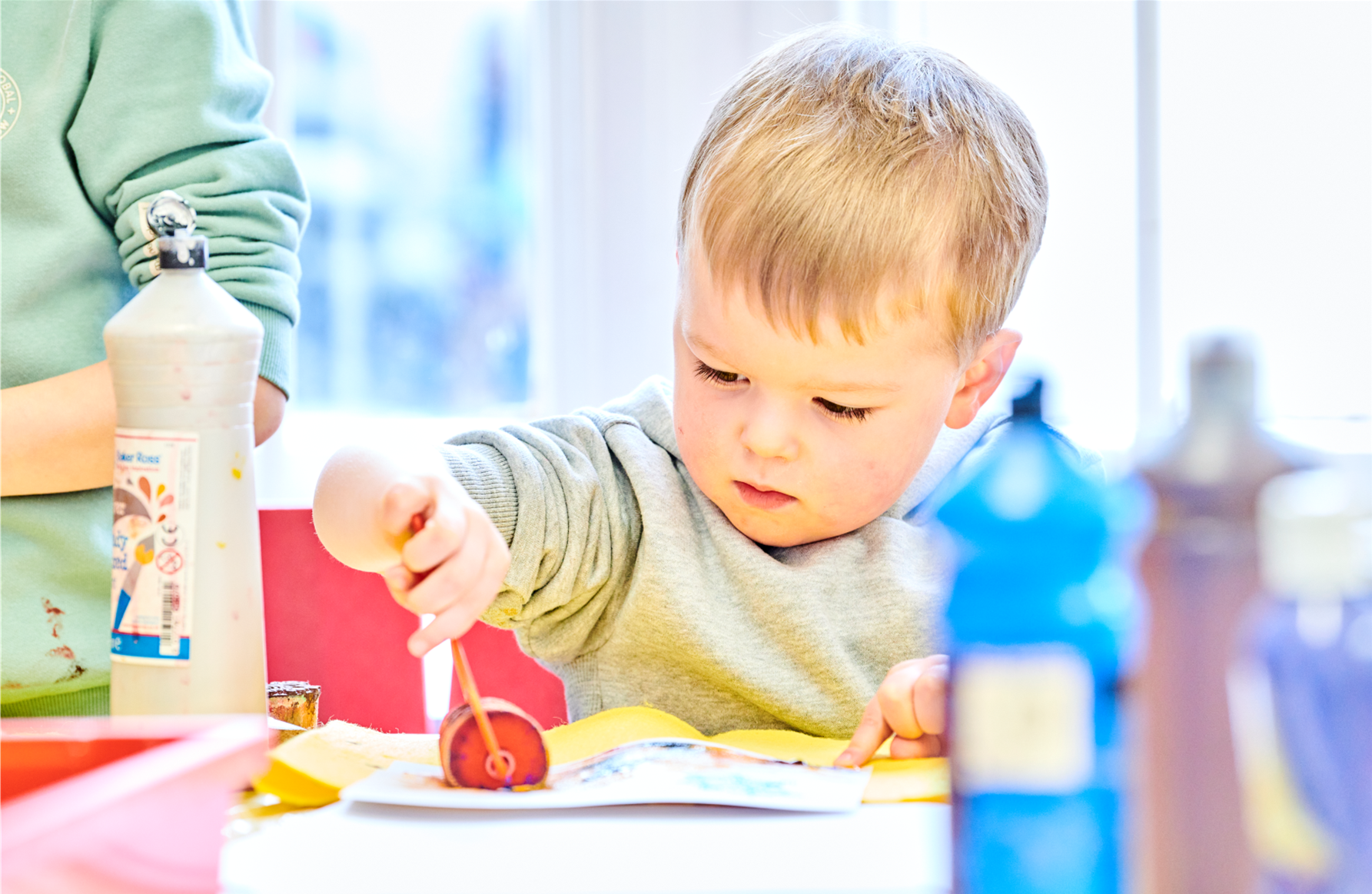 A Small Child is playing with a roller making a piece of art