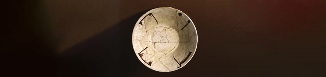 View from above of the inside of a white ceramic bowl, decorated with a style of angular writing known as Kufic.