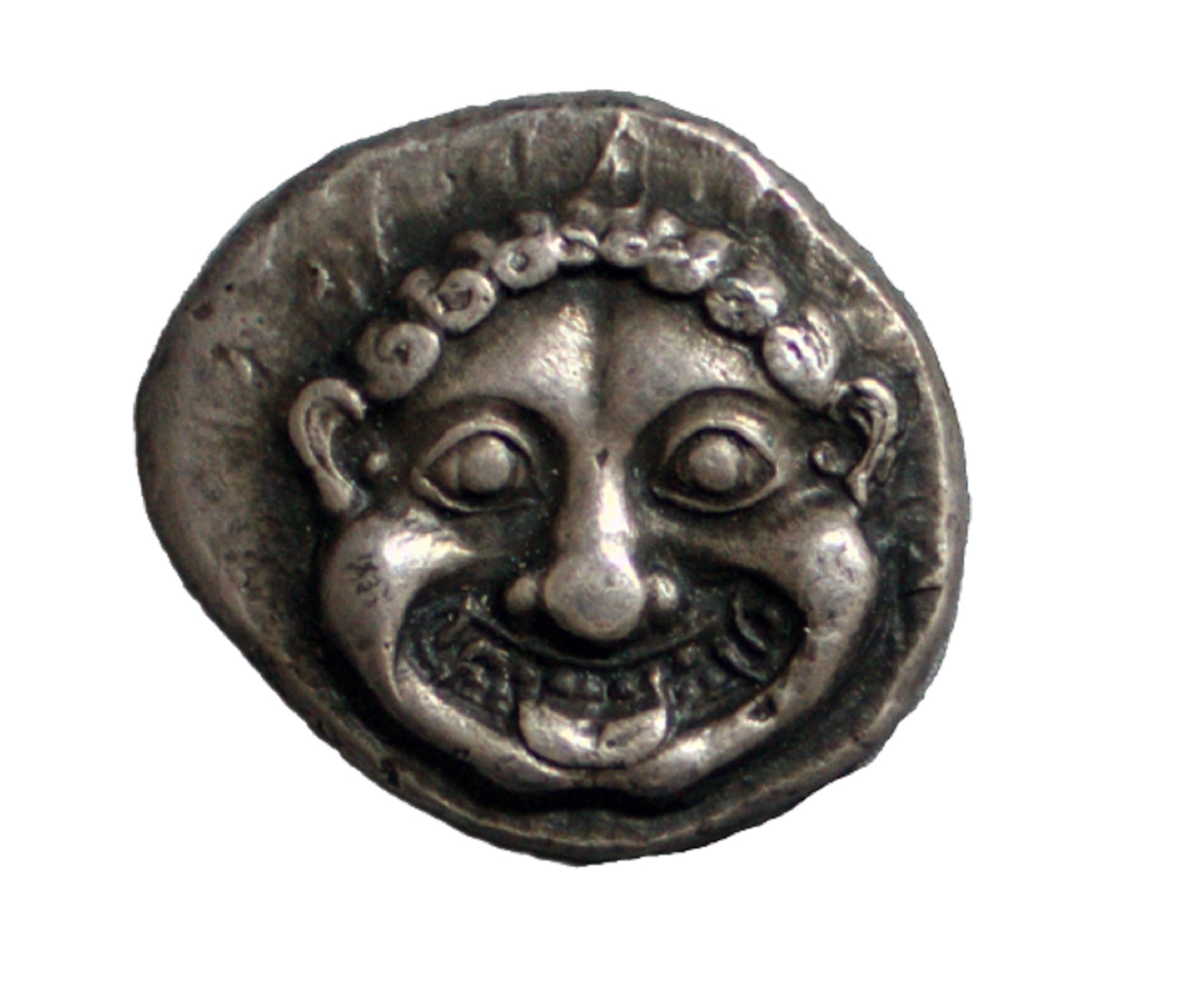 A 19th-century electrotype copy of an Ancient Greek coin depicting a Gorgon. A non-circular coin on white background showing a Gorgon.