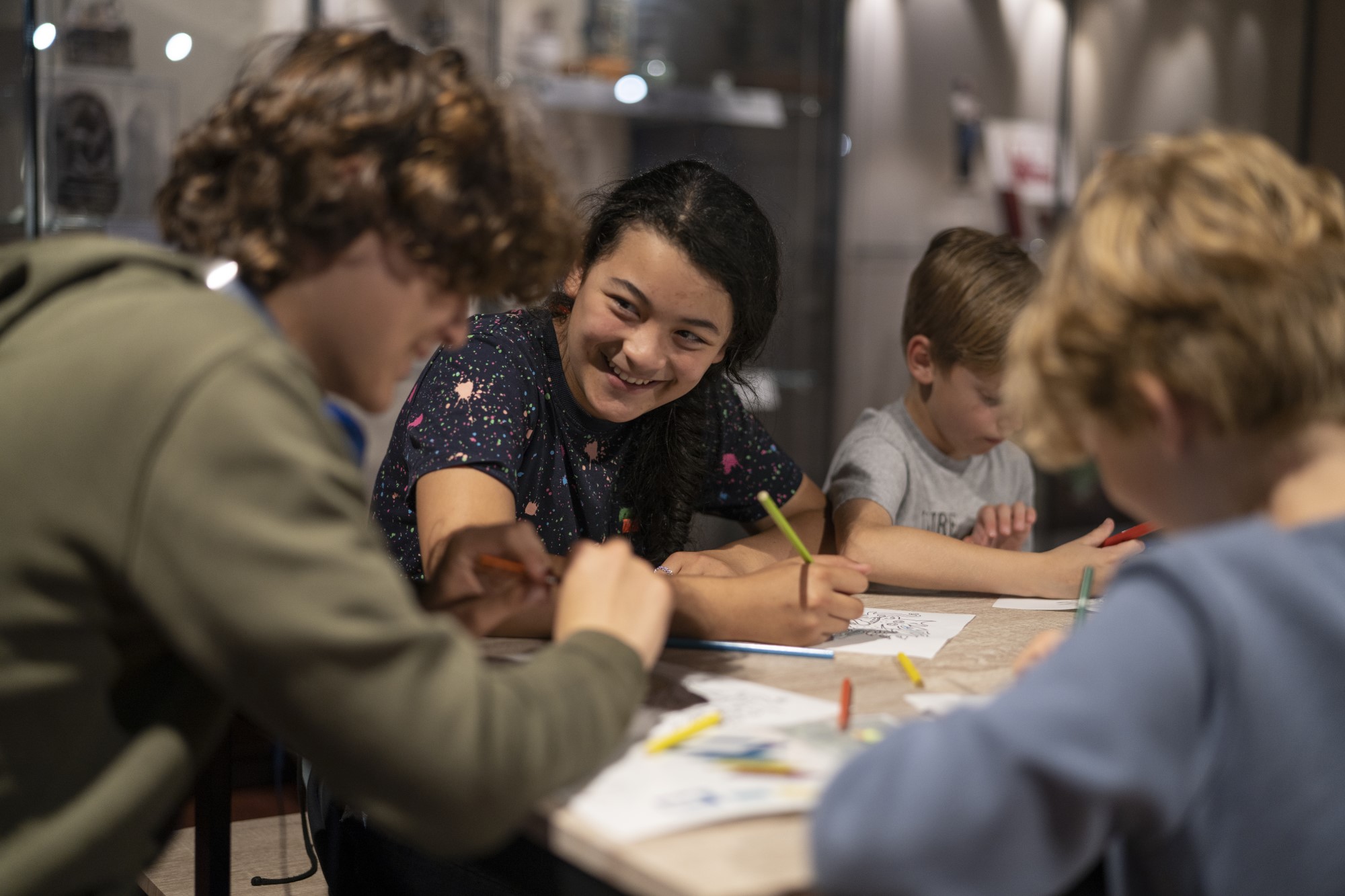 Young people sat around a craft table smiling