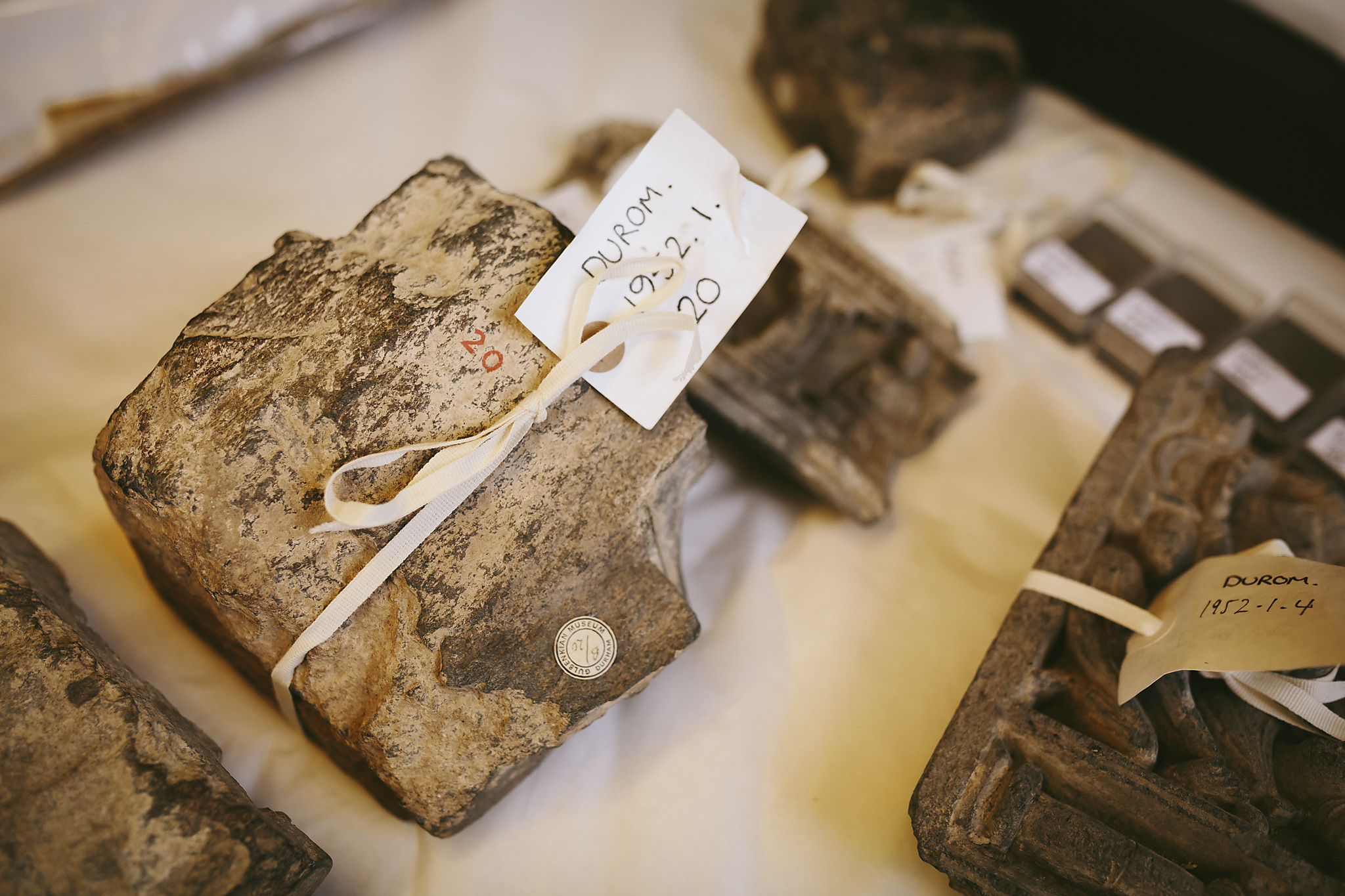 Group of stone objects with ties around them to attach labels, with museum object numbers tied to them